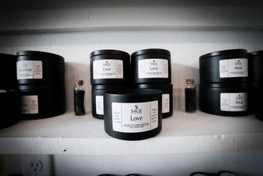 A shelf filled with black jars of candles and bottles.