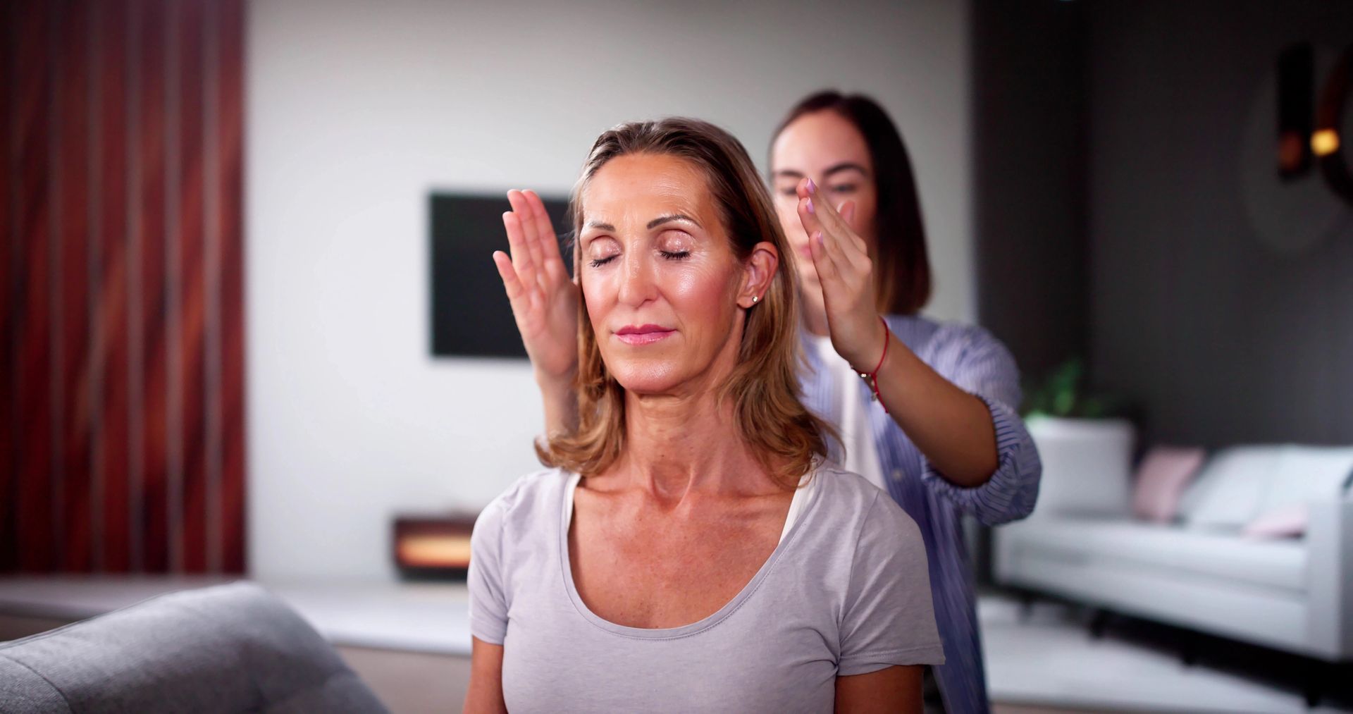A woman is getting a massage from another woman in a living room.