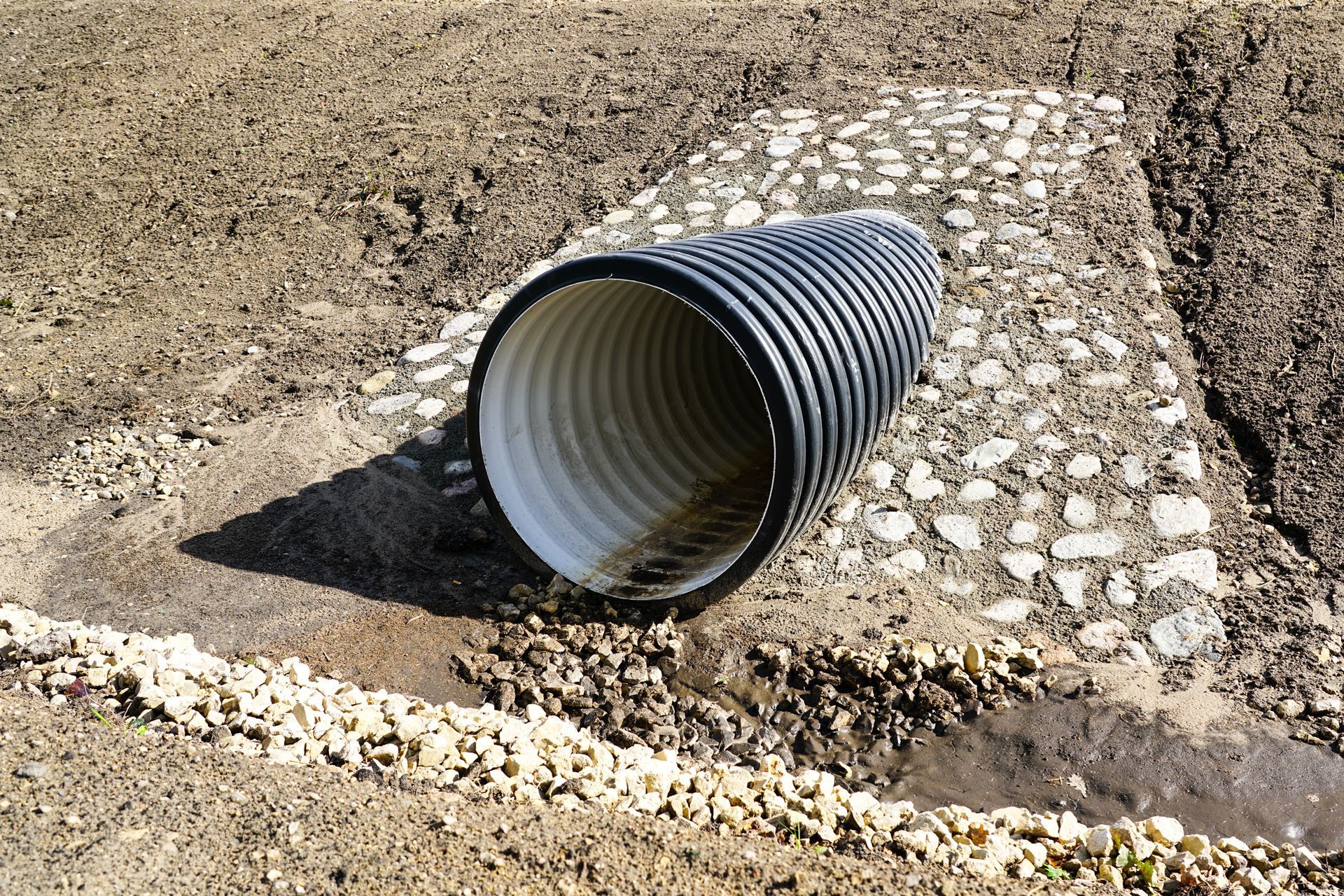 A black and white culvert is sitting in the dirt