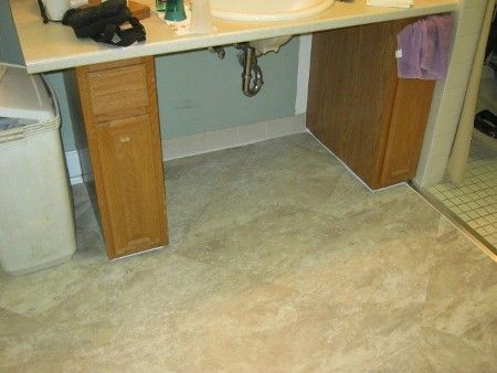Under-desk carpeted area with wooden cabinets and a trash can in an office or study space