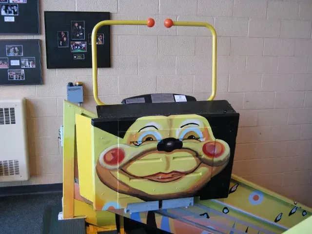 Cartoon-faced ride-on car with yellow handlebar in an indoor play area