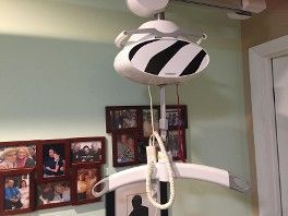 Ceiling-mounted baby swing with white seat and black accents in a room with framed photos.