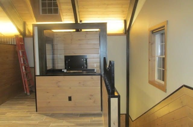 Loft interior with wooden stairs, a central TV cabinet, and warm ceiling lighting