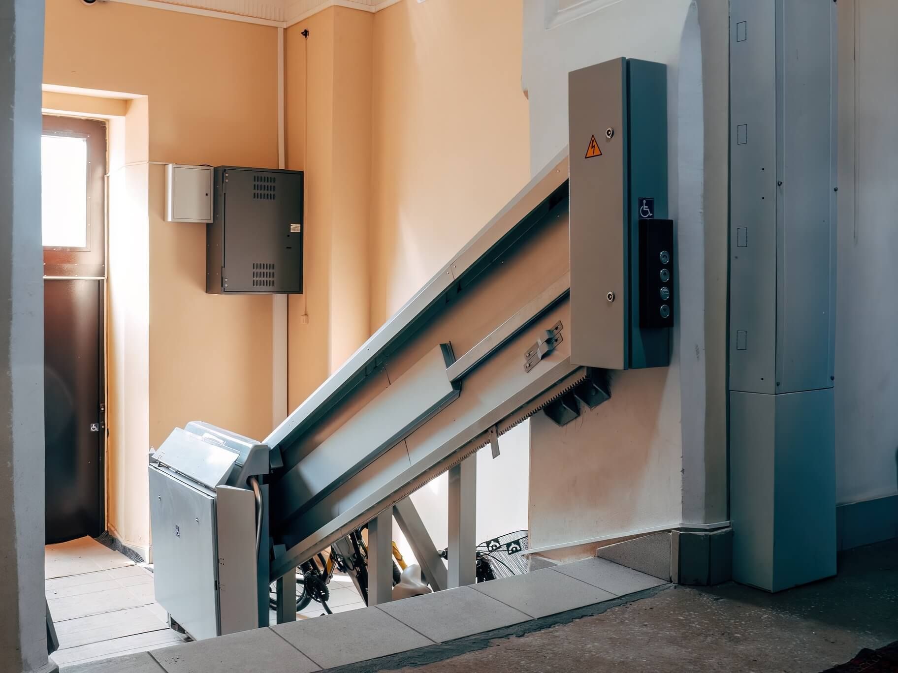 Indoor stair lift in a beige stairwell with a window and control panel