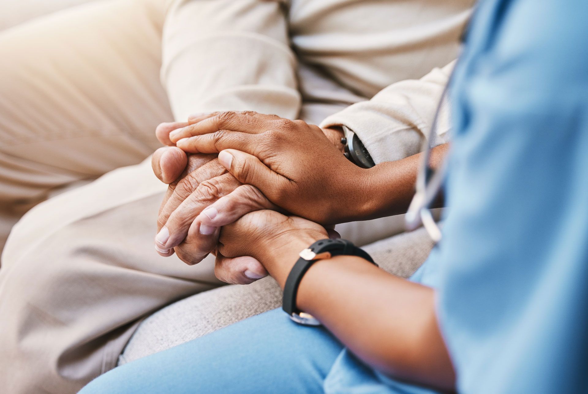 Hands clasped, medical professional comforts a person in a supportive gesture.