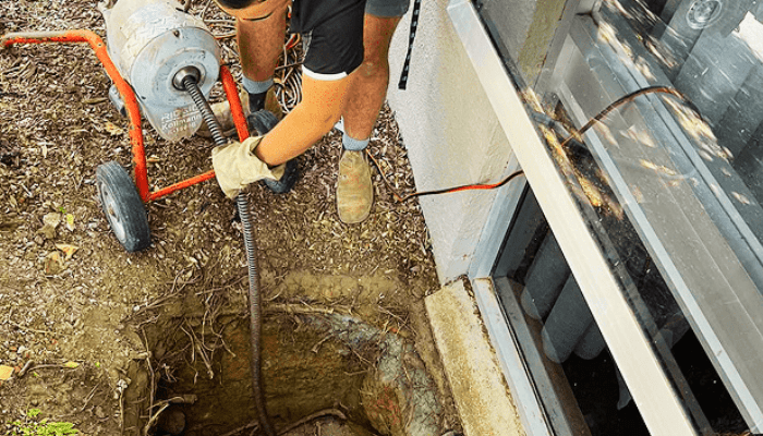 Pressure washer nozzle spraying a strong white stream onto a wet, pebbled surface