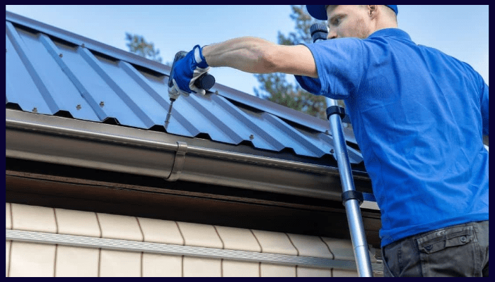 tradie installing metal gutters on a home using a drill
