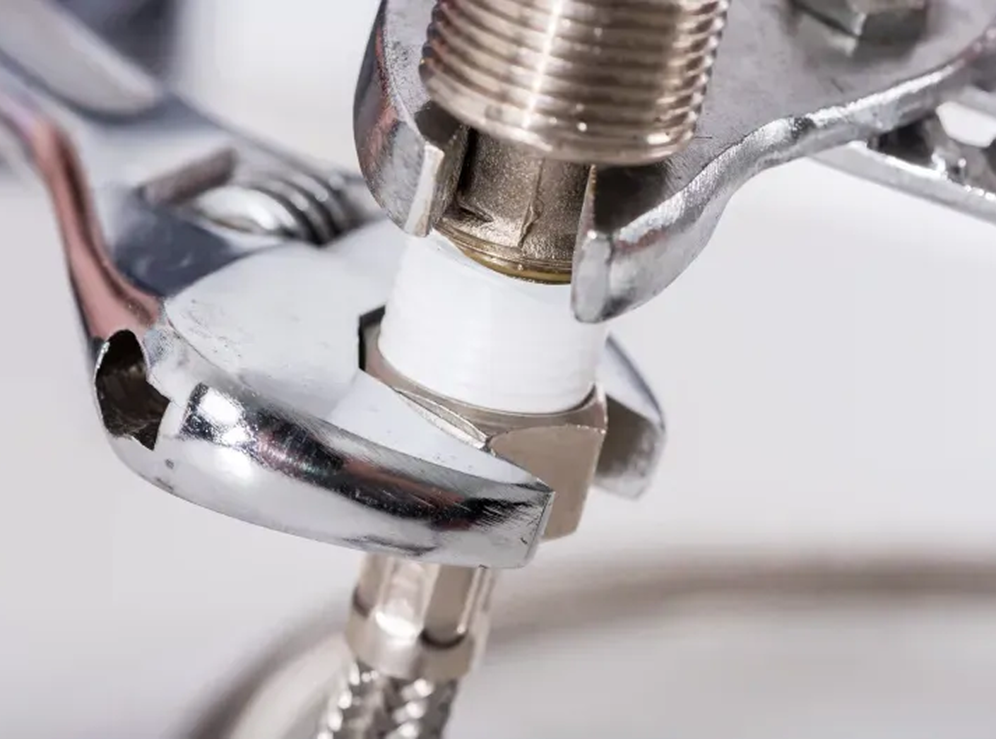 A wrench is being used to fix a faucet.