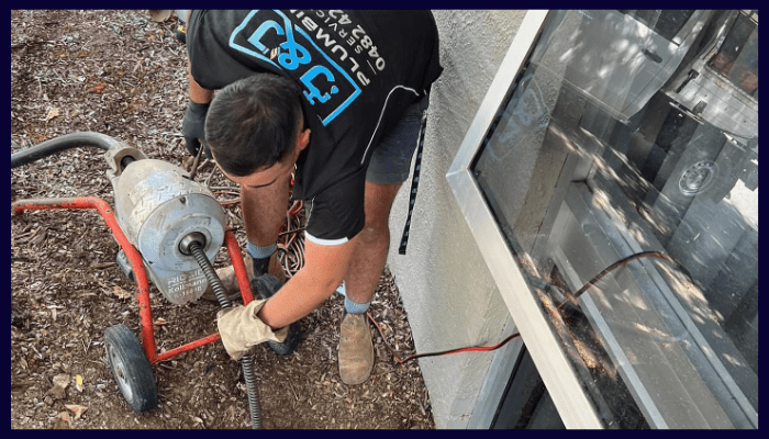 Plumber performing drain maintenance outside a Canberra home.