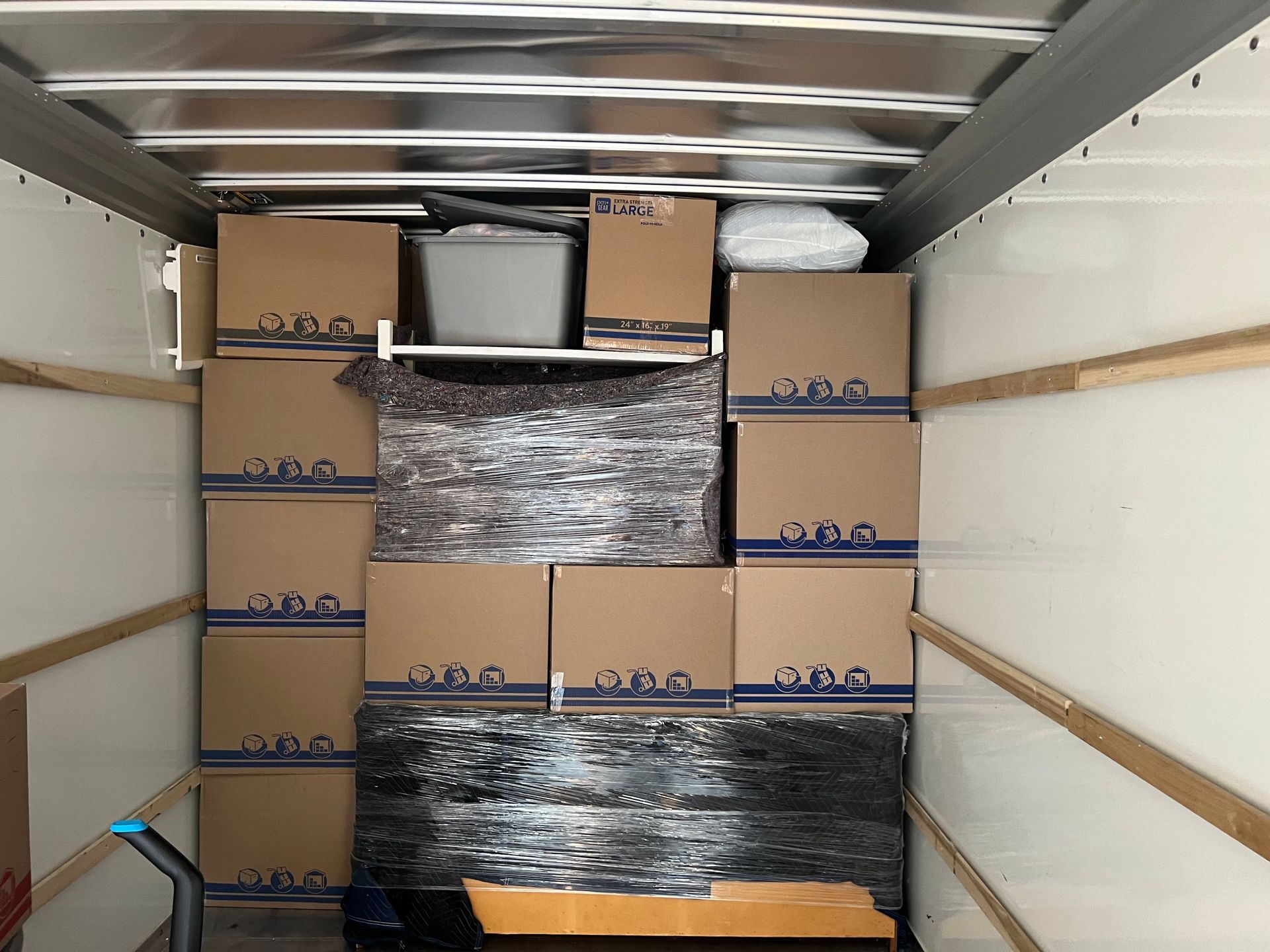 Interior of a moving truck packed with cardboard boxes and miscellaneous items, ready for transport.