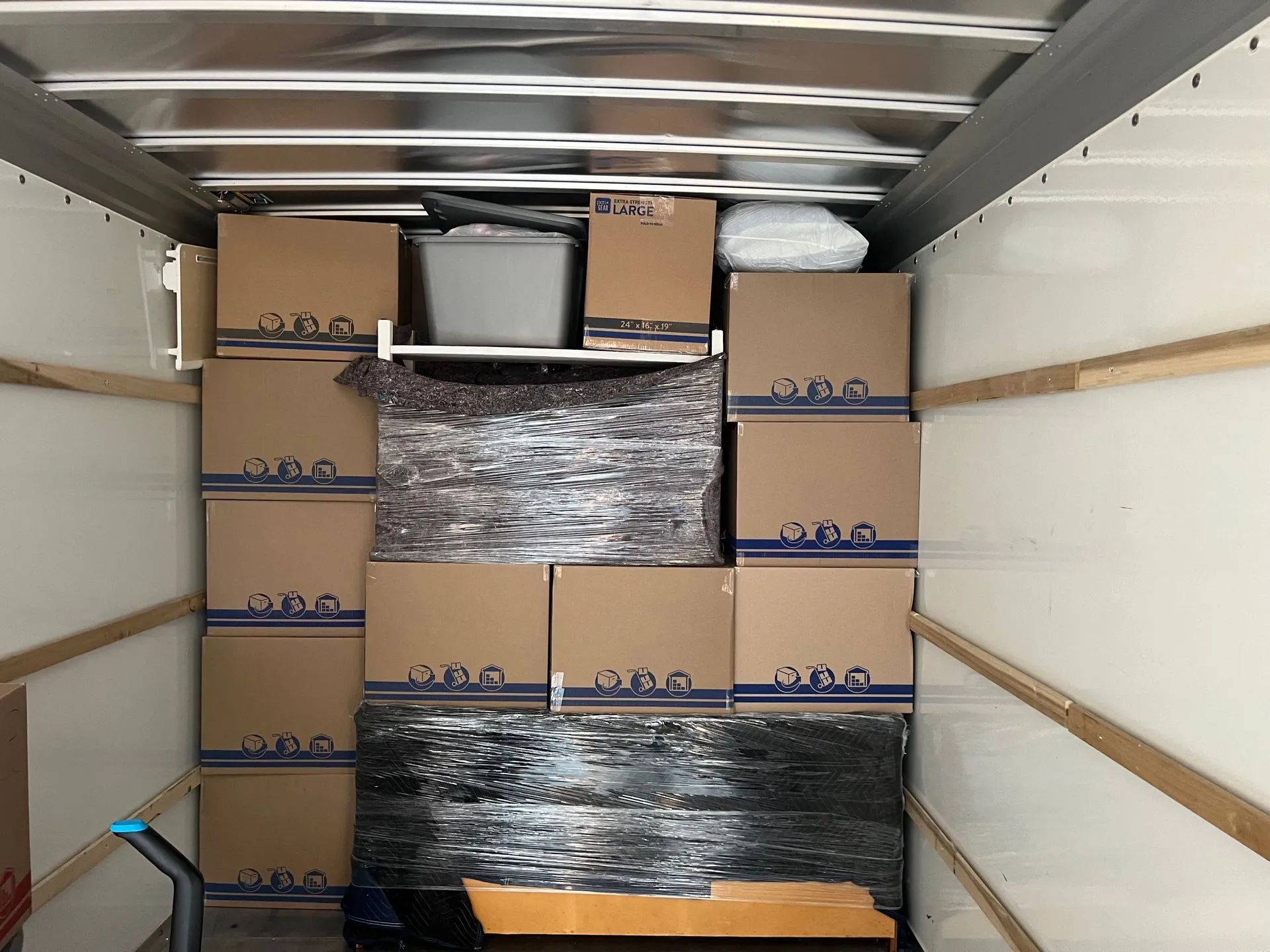 Packed moving truck with stacked cardboard boxes and furniture secured inside