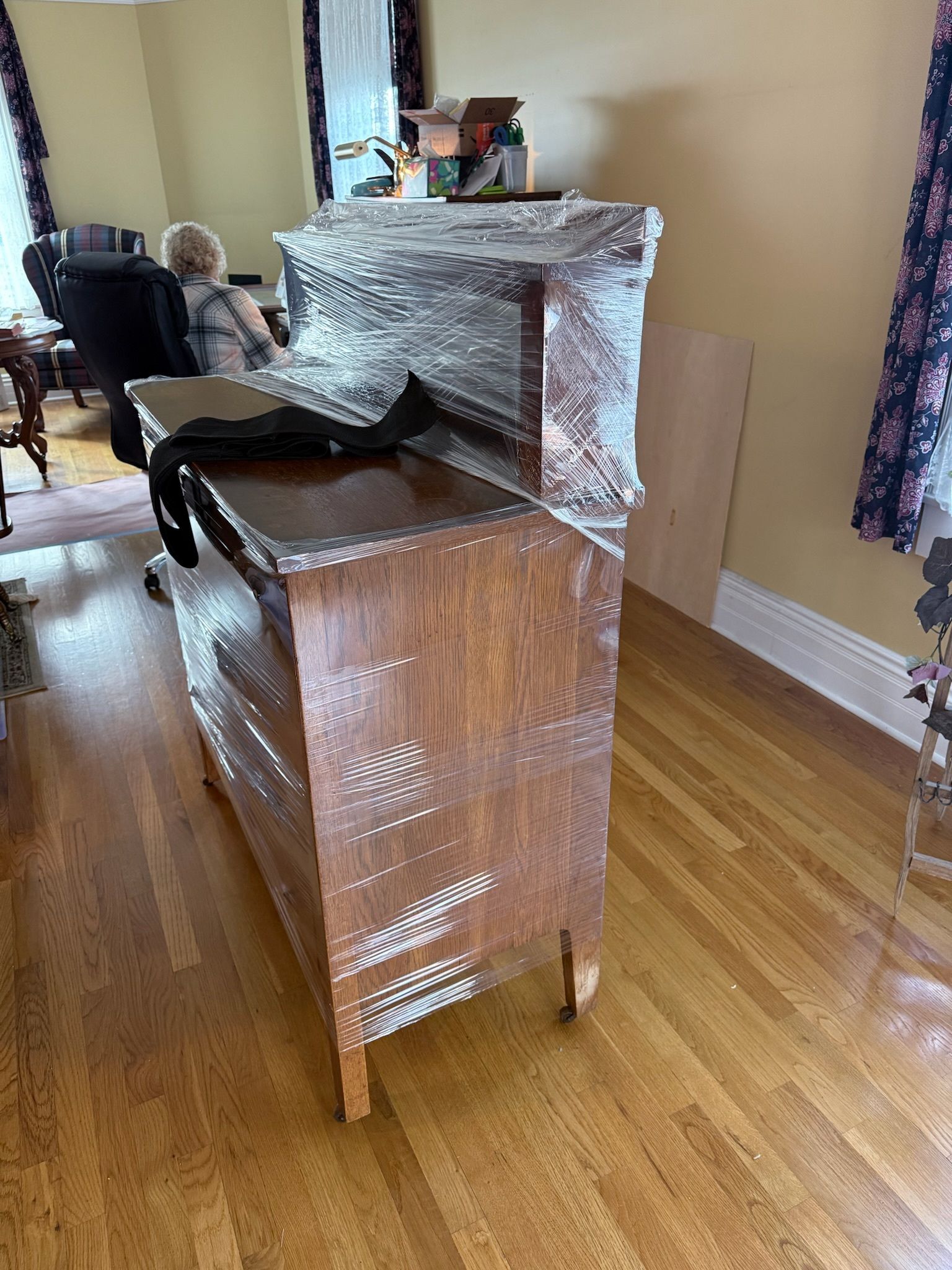 Wrapped furniture in a room, including a chair and cabinet covered in bubble wrap.
