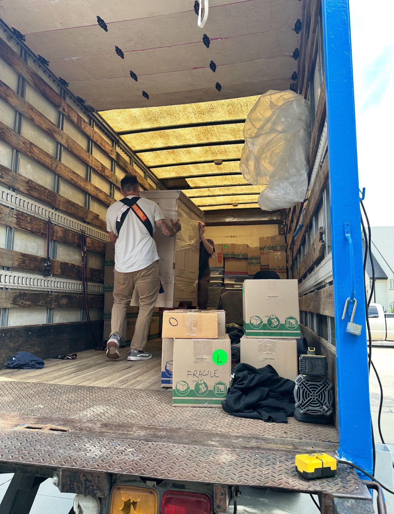Movers loading boxes and furniture into a truck. Inside the truck, several boxes and a lamp are visible.
