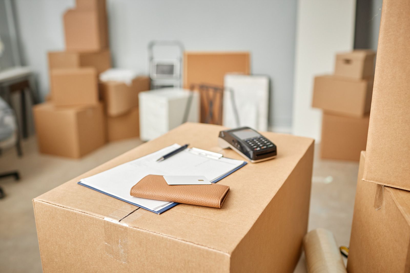 Cardboard boxes, clipboard, payment terminal, moving supplies.