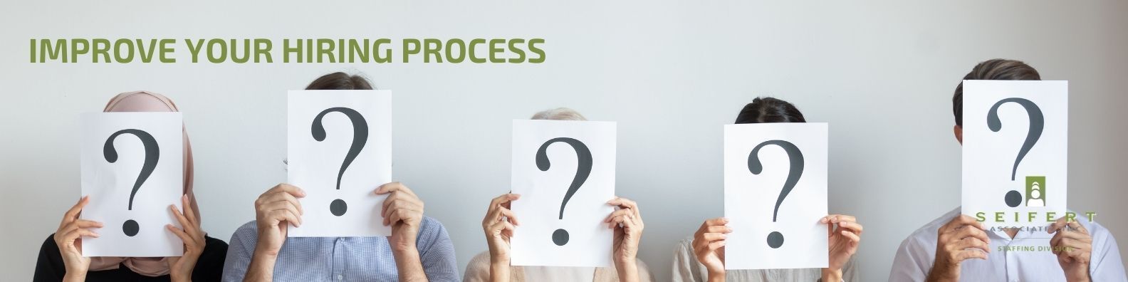 Text: Hiring process. Three people are holding up sheets of paper with a large question mark obscuring their faces.