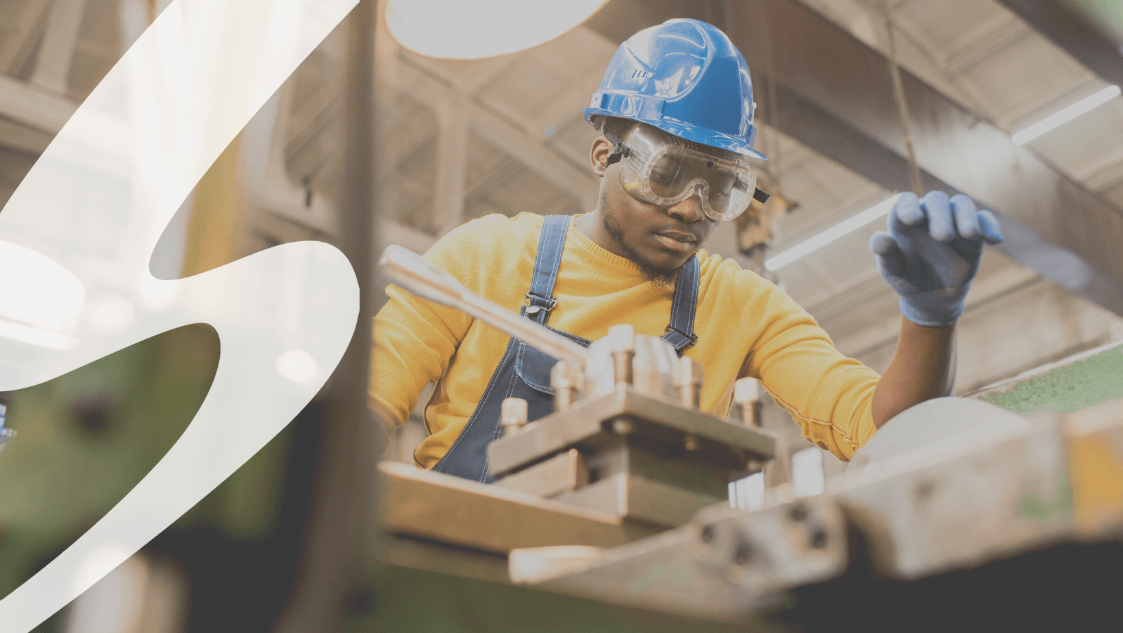 A man in a hard hat at the controls of a machine.