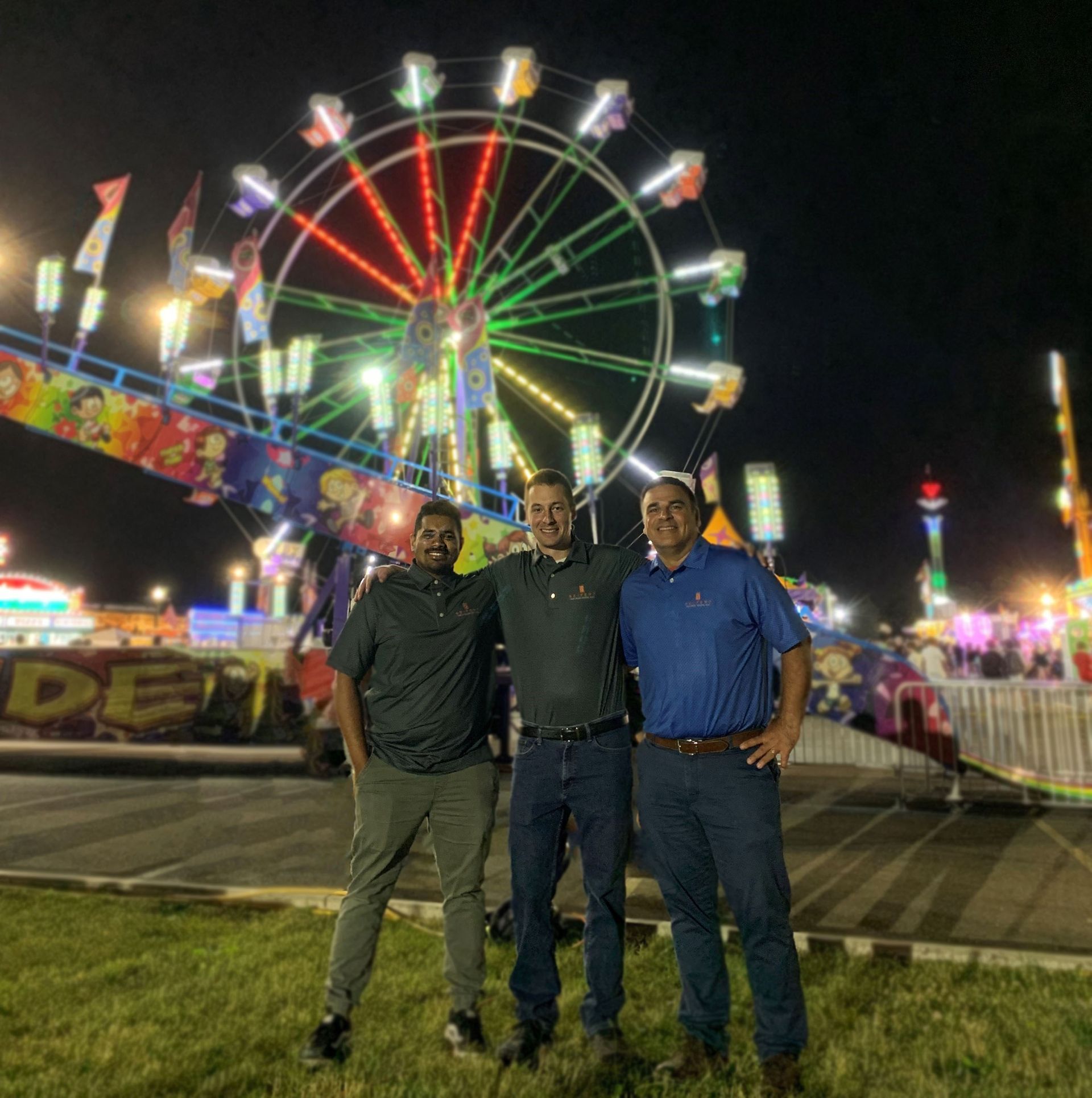 Three Seifert employees at a festival, a Ferris wheel is in the background