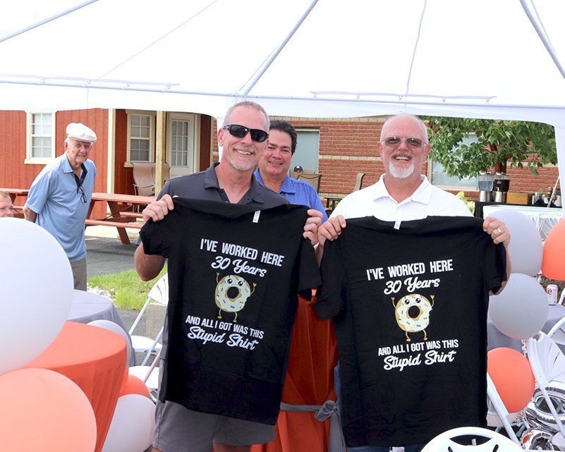 Left to right Eric, Tim, and John holding shirts that say 