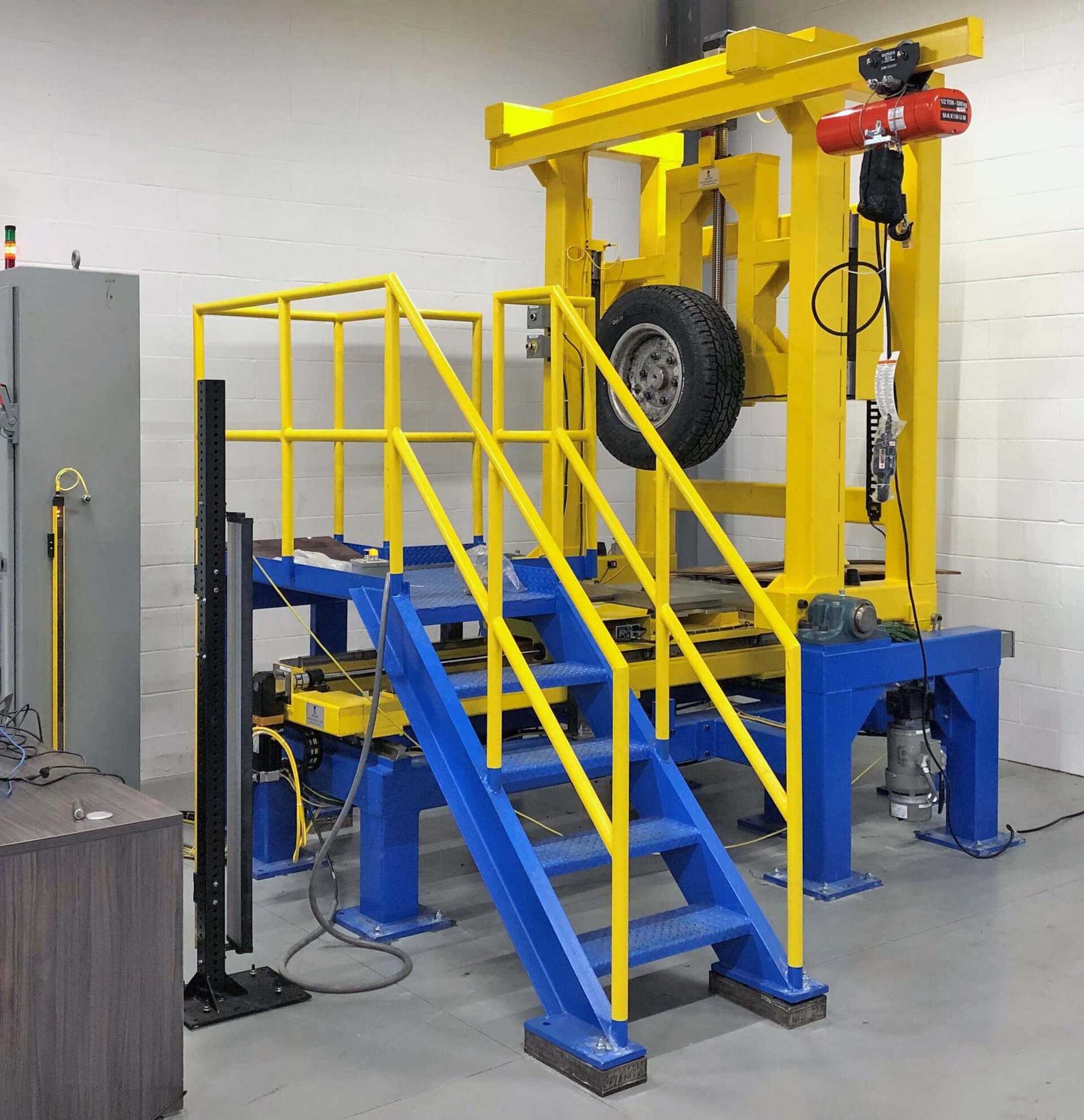 Tire pressure machine. A tire is mounted on a metal frame, and a staircase leads up to the testing area.