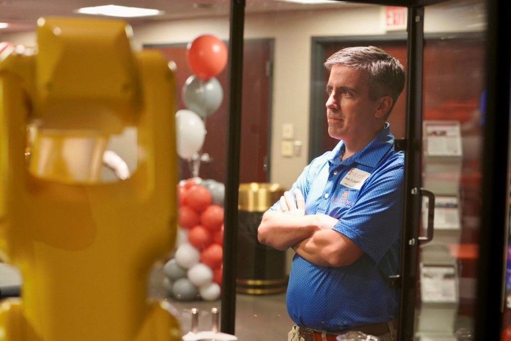 Seifert employee in front of a robotic arm, with his hands crossed.