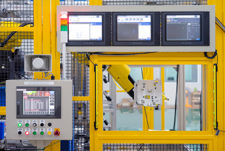 The controls to a robotic arm. There are 4 monitors and multiple buttons.