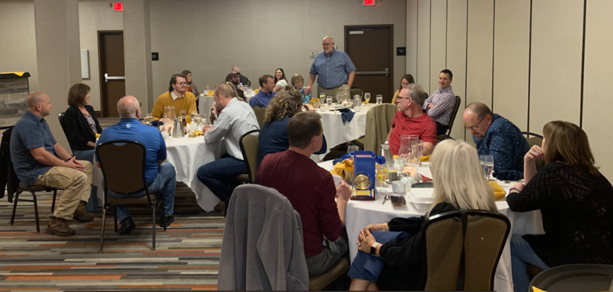 Seifert Technologies employees seated at a couple of round tables with tablecloths.