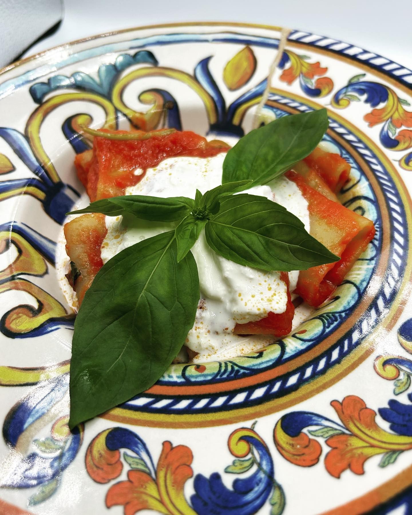 Piatto di insalata caprese con foglie di basilico su un piatto decorato.