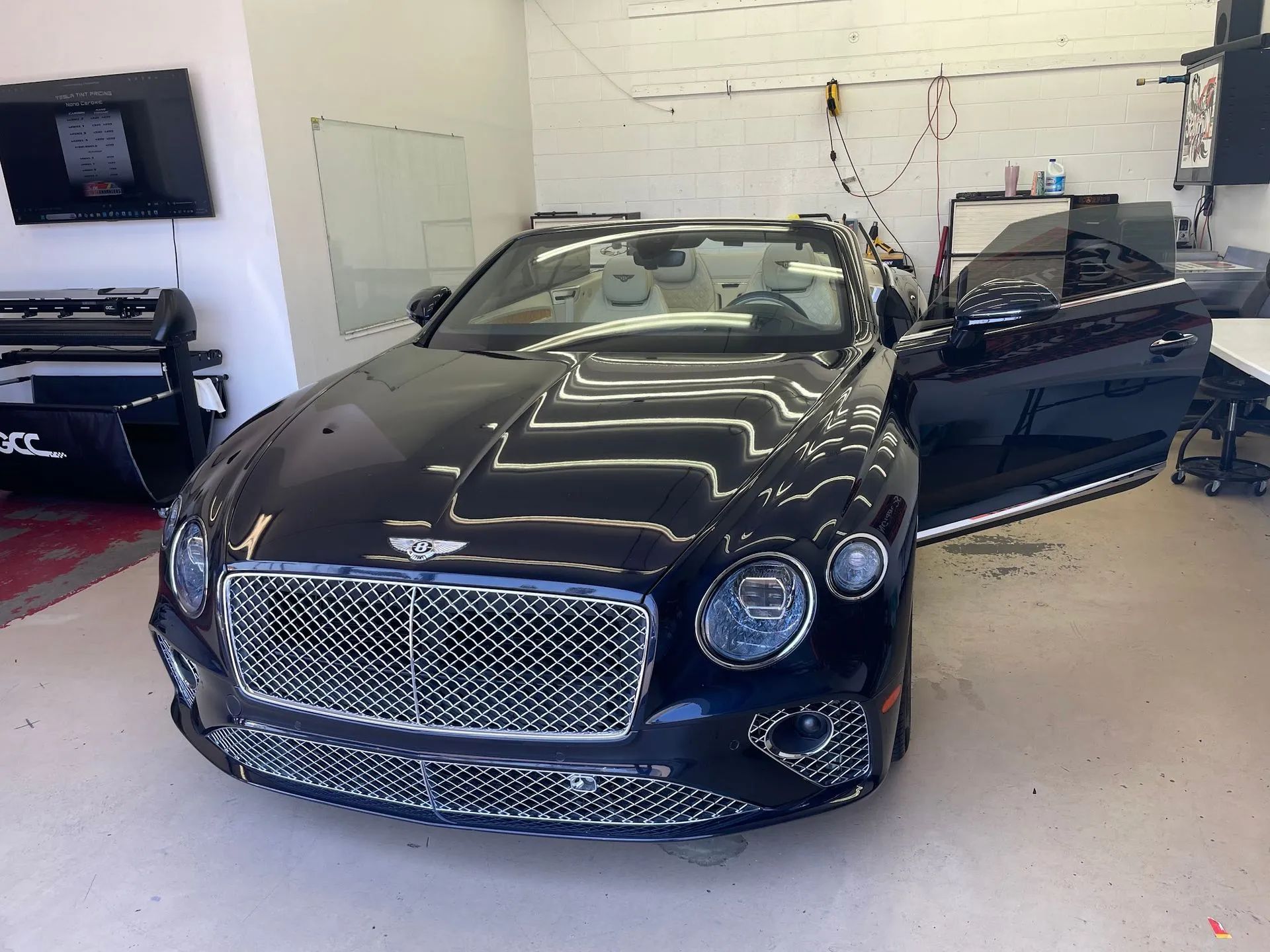 Black luxury car in a garage with the driver’s door open