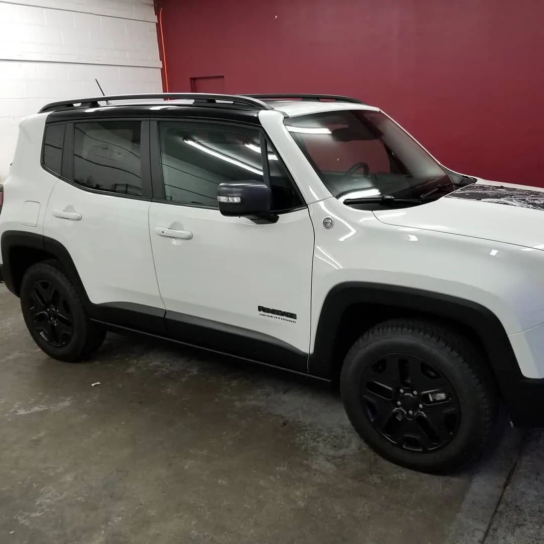 White SUV with black roof and wheels parked indoors against a red wall