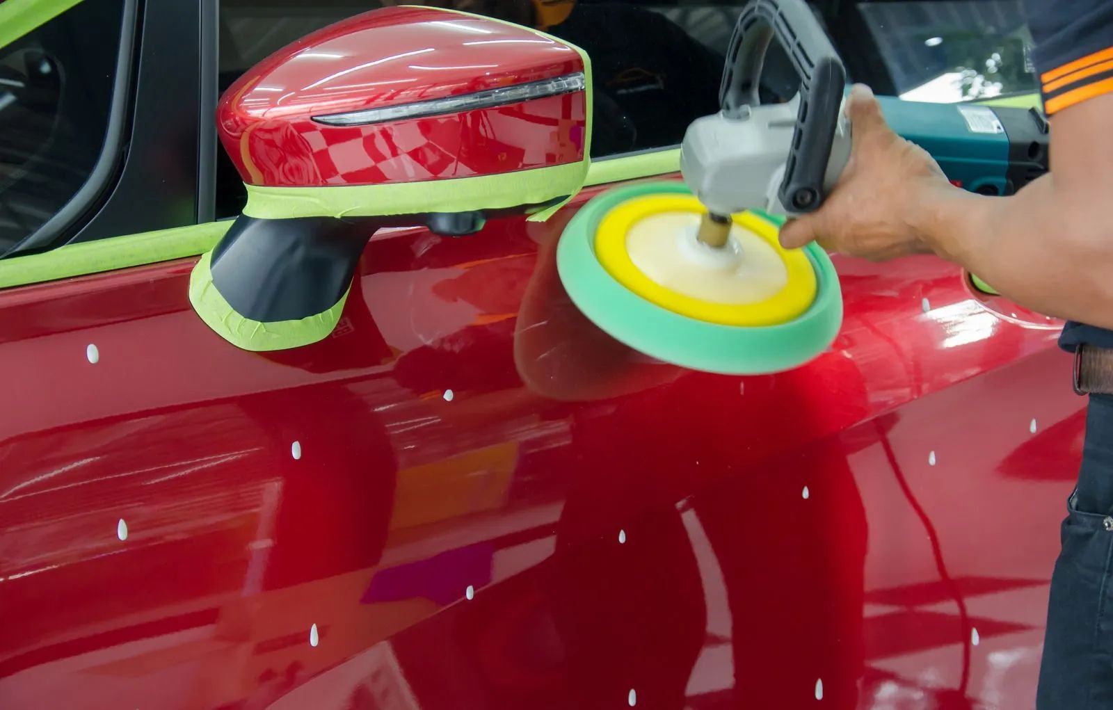 Buffer polishing a red car door with a rotary polisher
