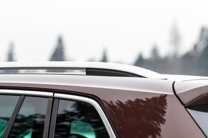 Brown SUV, chrome roof rack, overcast sky with trees in the background.