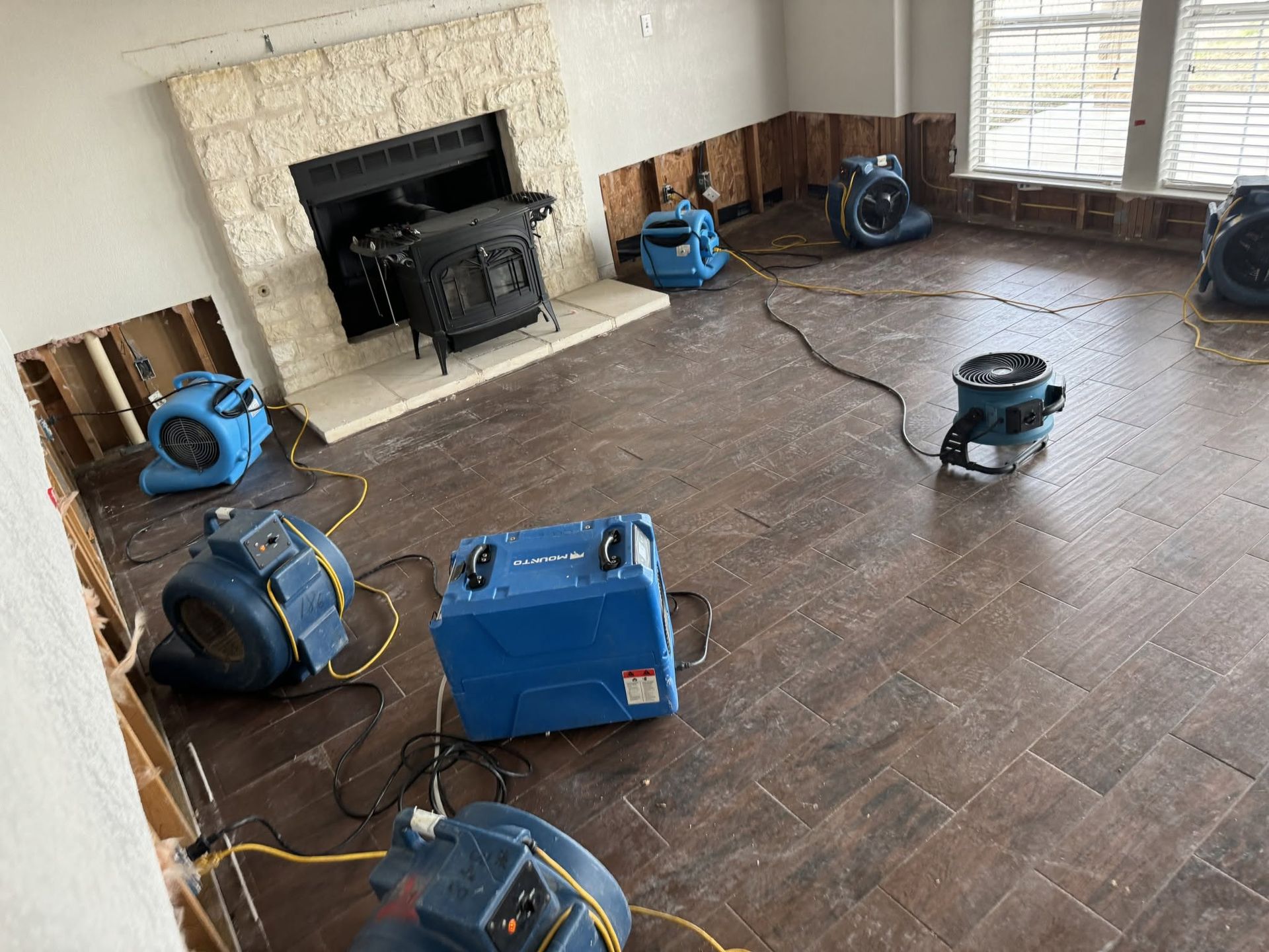 Living room with floor buffers and cleaning machines around a fireplace, preparing to clean the wood floor