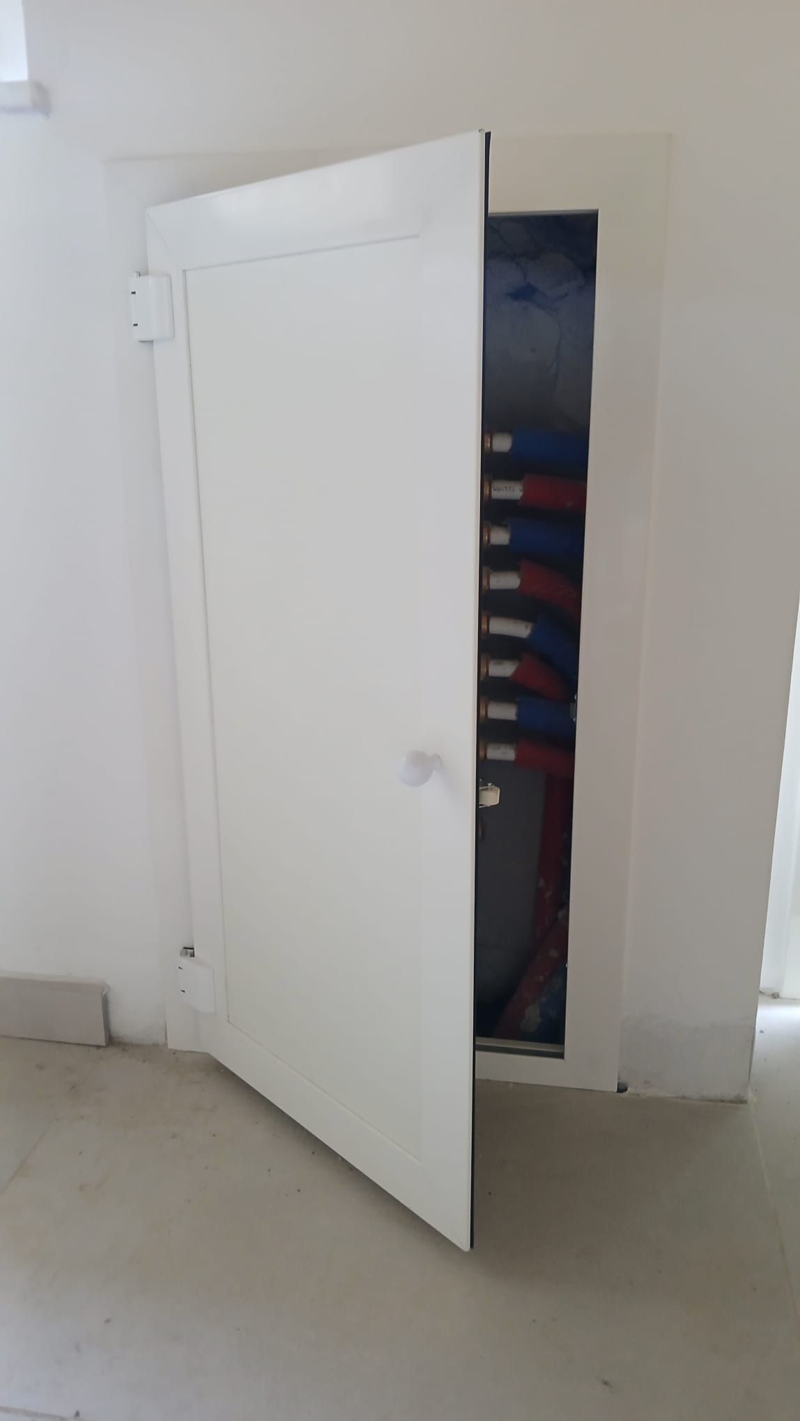 Aprendo una porta bianca si scopre un armadio con all'interno abiti piegati e impilati.