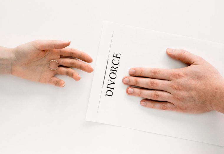 One person holds a wedding ring toward another person who is pressing their hand onto a paper labeled