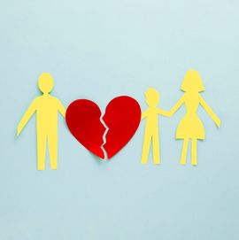 Paper cutouts of a man, woman, and child separated by a broken red heart on a light blue background.