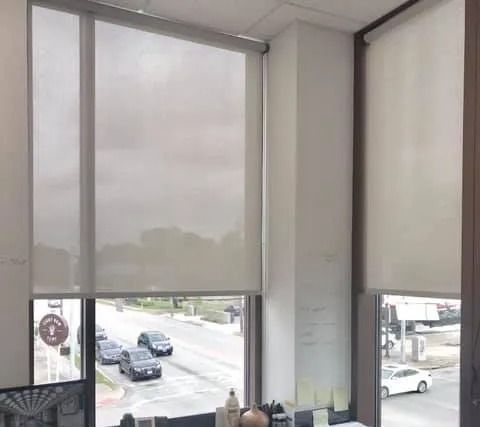 Interior corner with three window shades overlooking a street with cars.