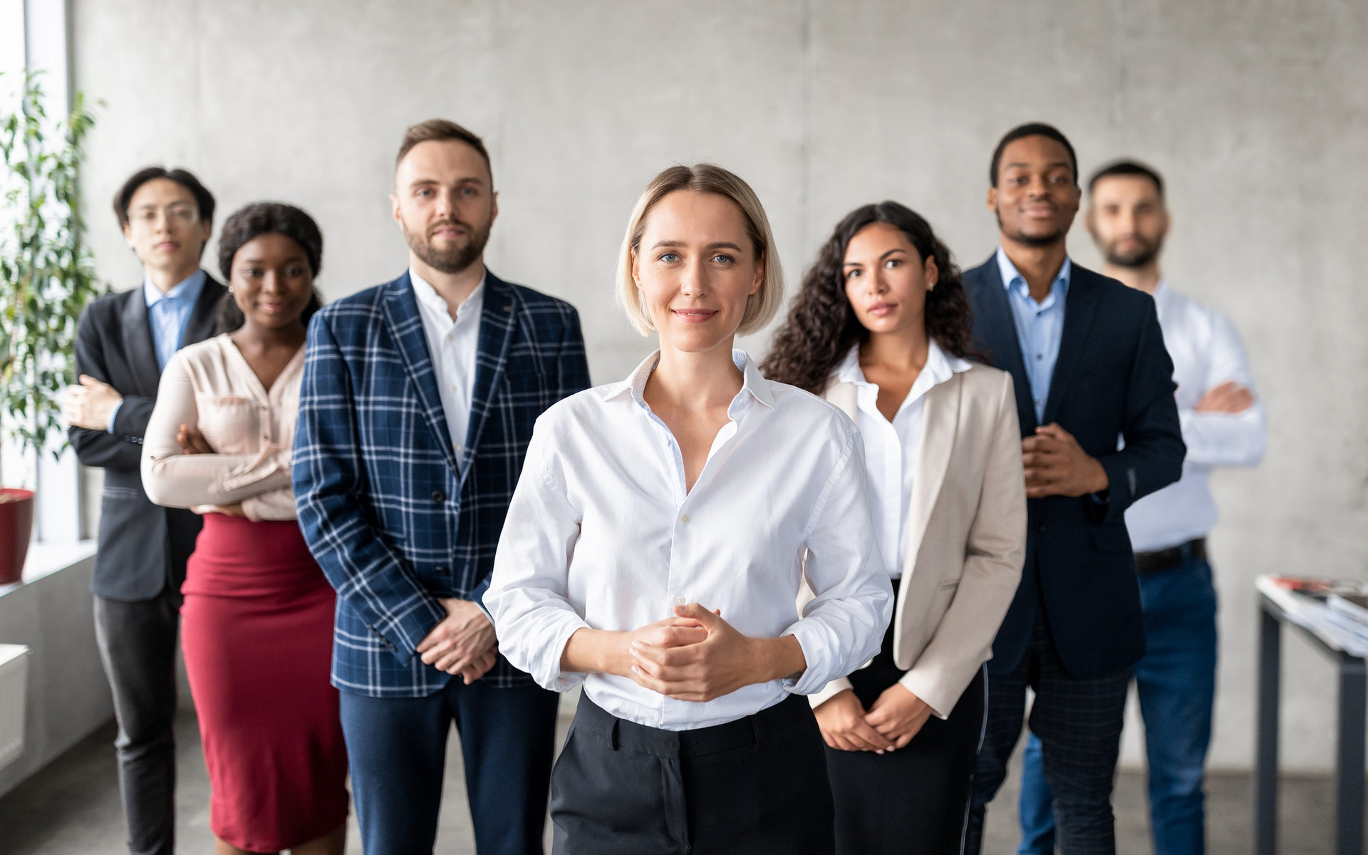 Group of people in business attire standing together indoors.