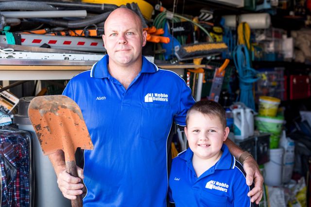 A man and a boy are standing next to each other in a self storage shed in Tamworth holding shovels.