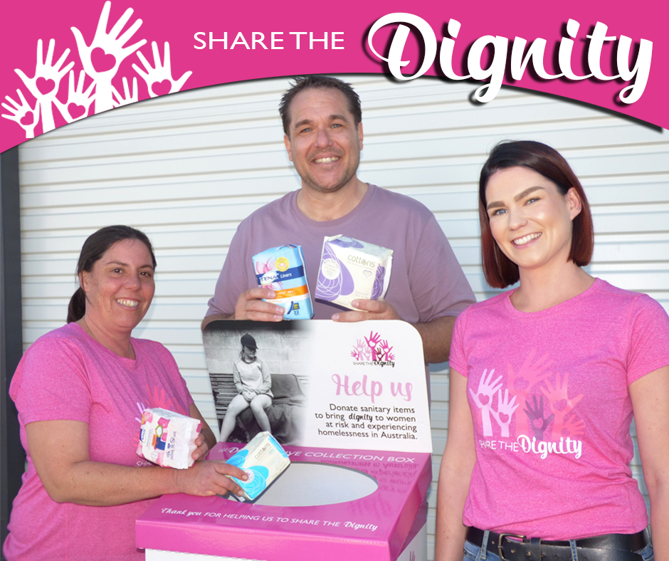 A man and two women are standing in front of a sign that says share the dignity