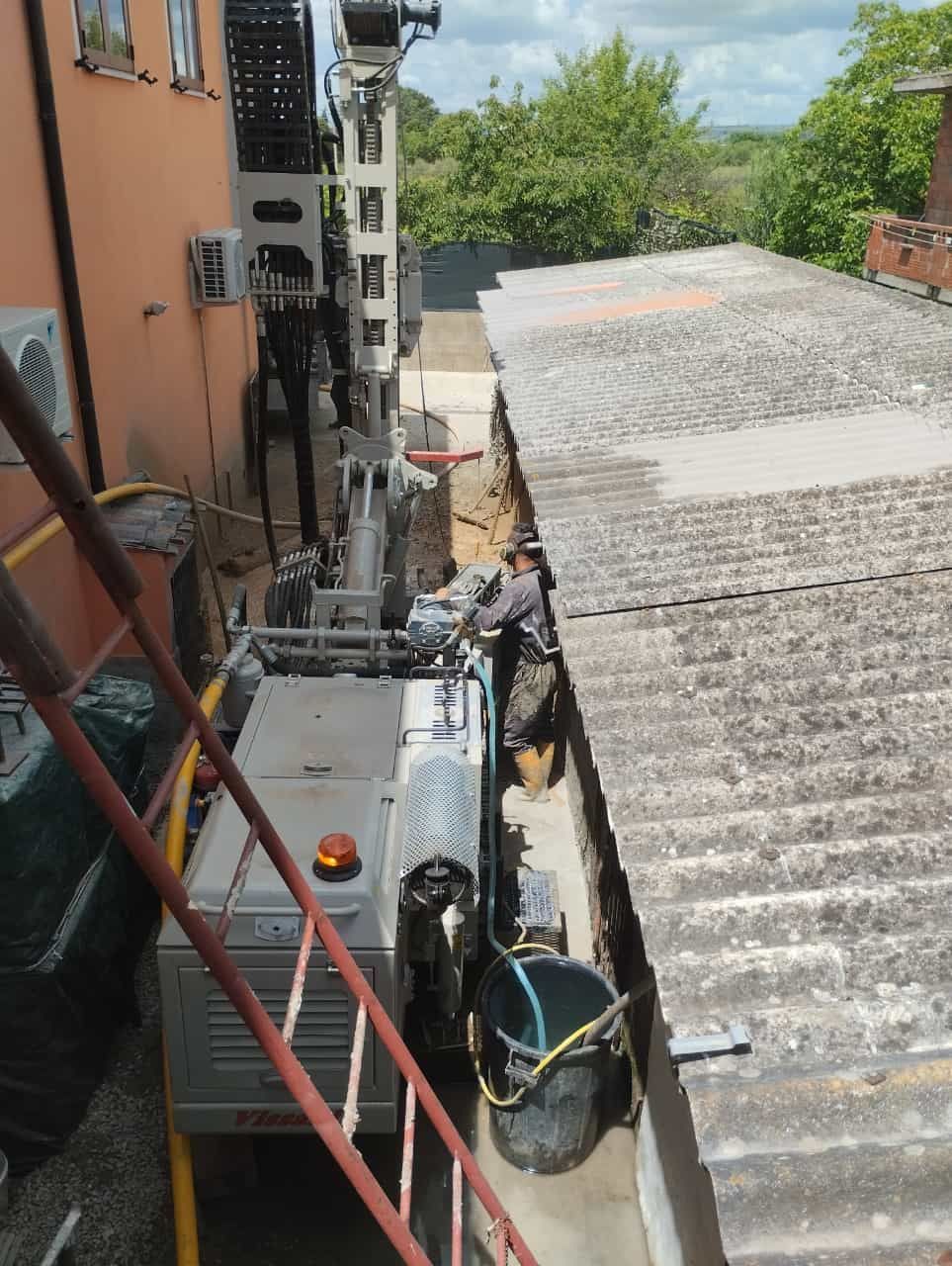 Uomo che aziona macchinari tra due edifici; sono presenti una scala e un camion dei pompieri.