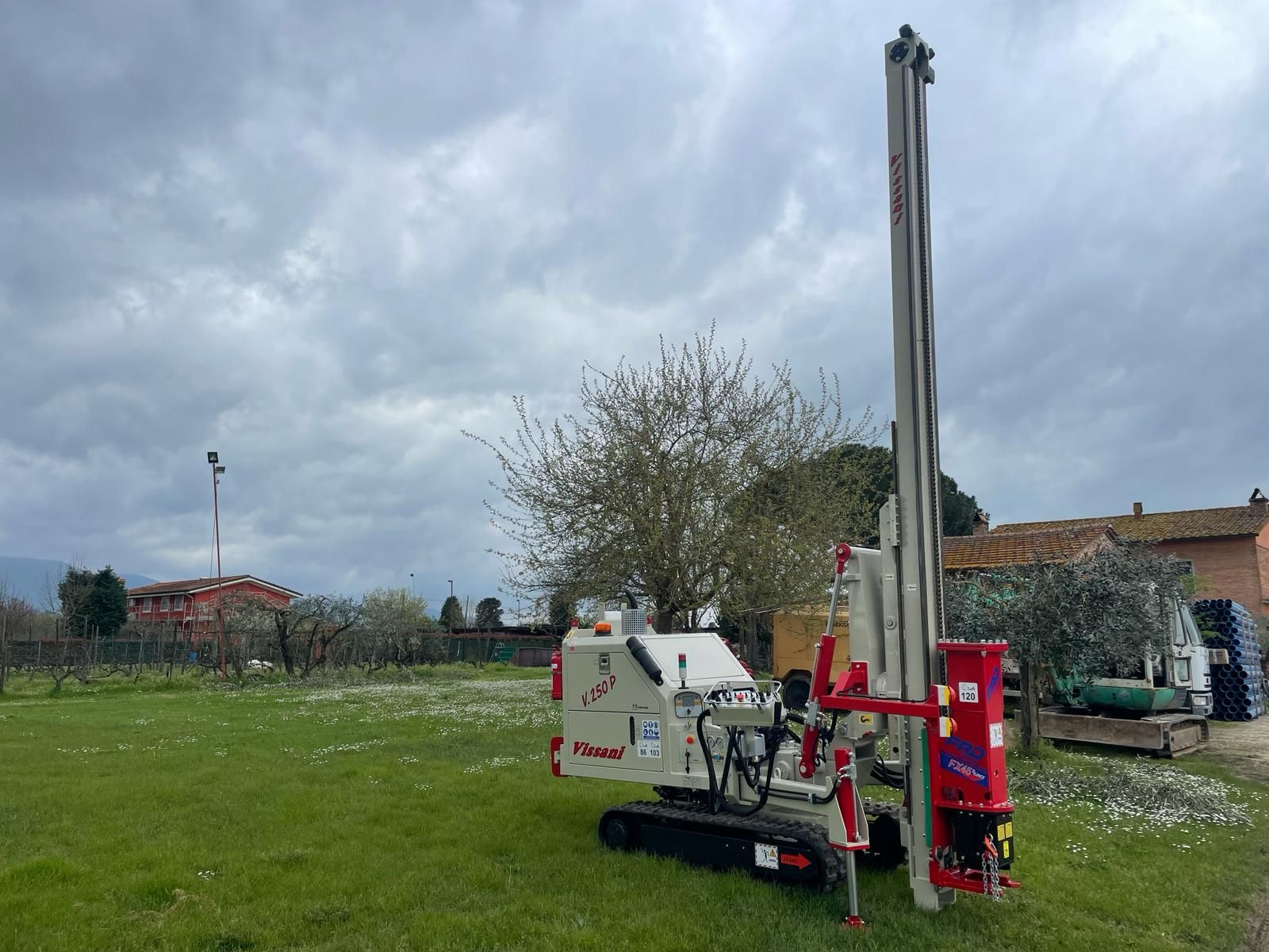 Una trivella su un campo erboso con un edificio sullo sfondo sotto un cielo nuvoloso.