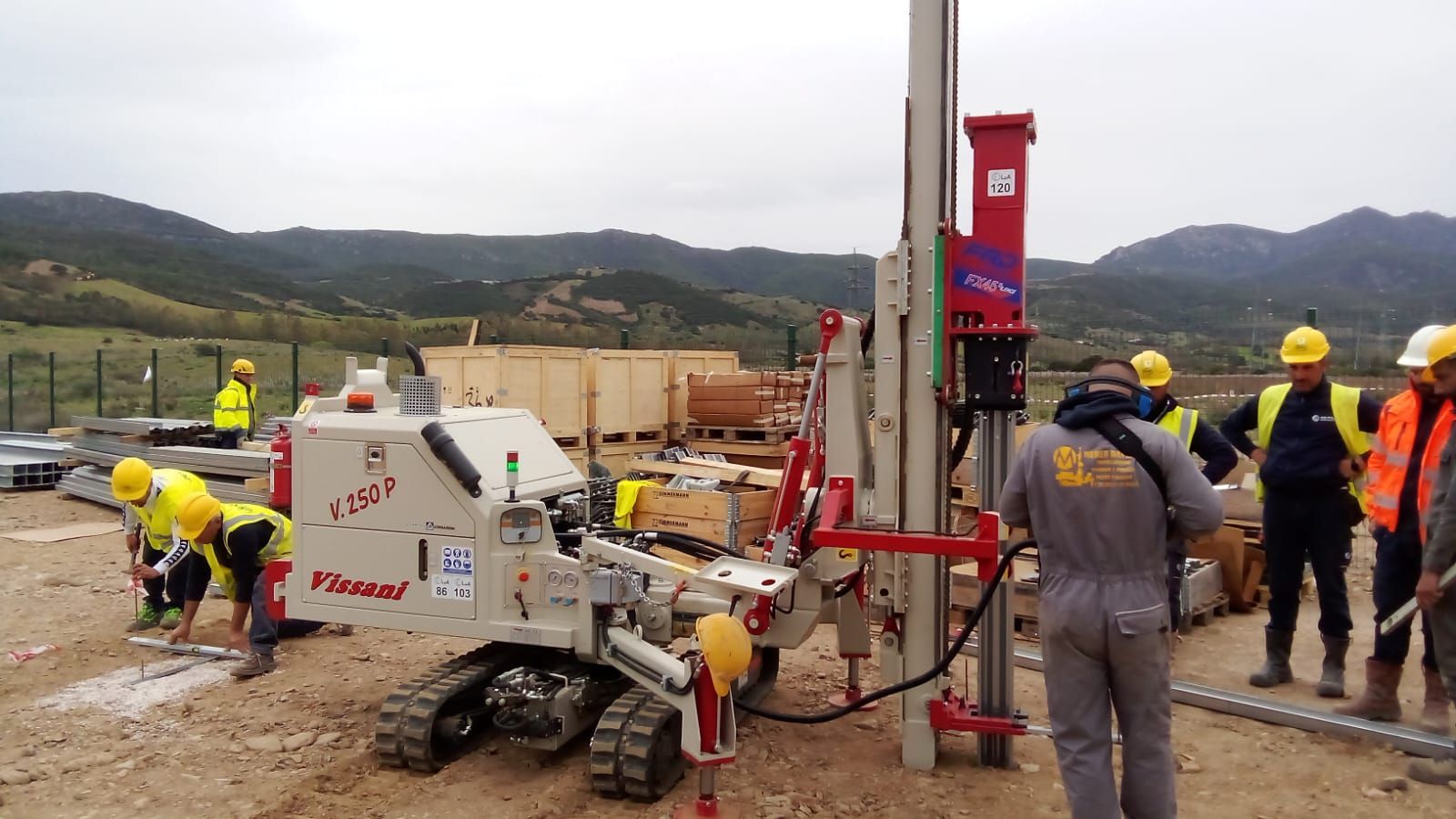 Gli operai azionano una perforatrice in un cantiere edile vicino alle montagne.