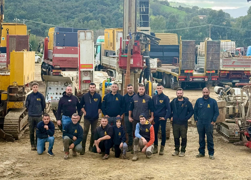 Un gruppo di operai in uniforme nera posa con una macchina GEO 700 A in un ambiente esterno.