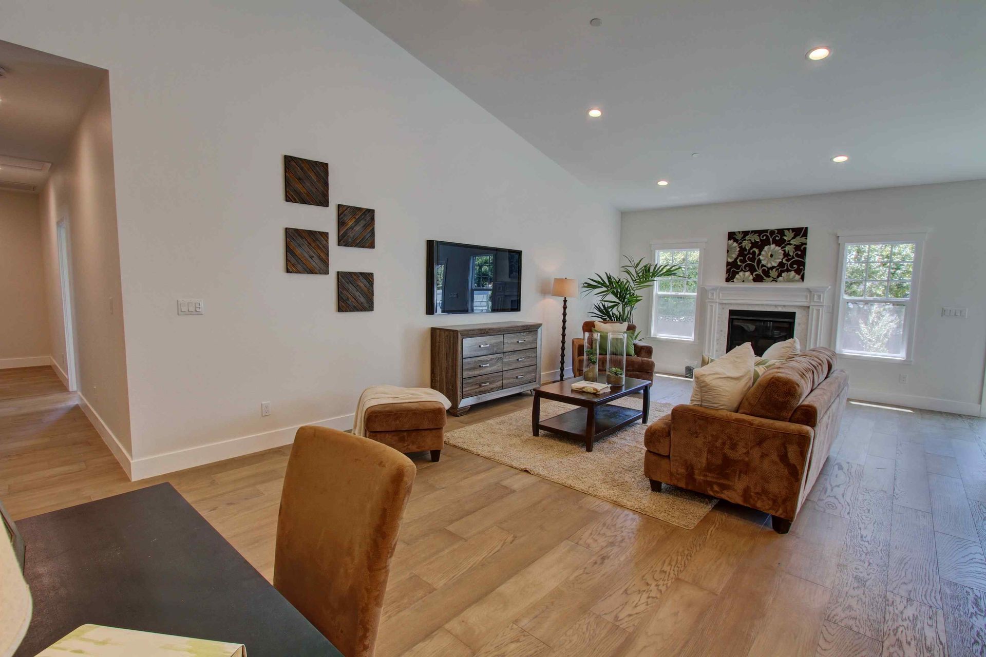 Bright living room with beige sofa, armchairs, TV, fireplace, and light wood floors.