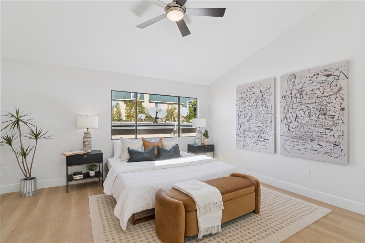 Bright minimalist bedroom with a bed, bench, nightstands, window, and wall art