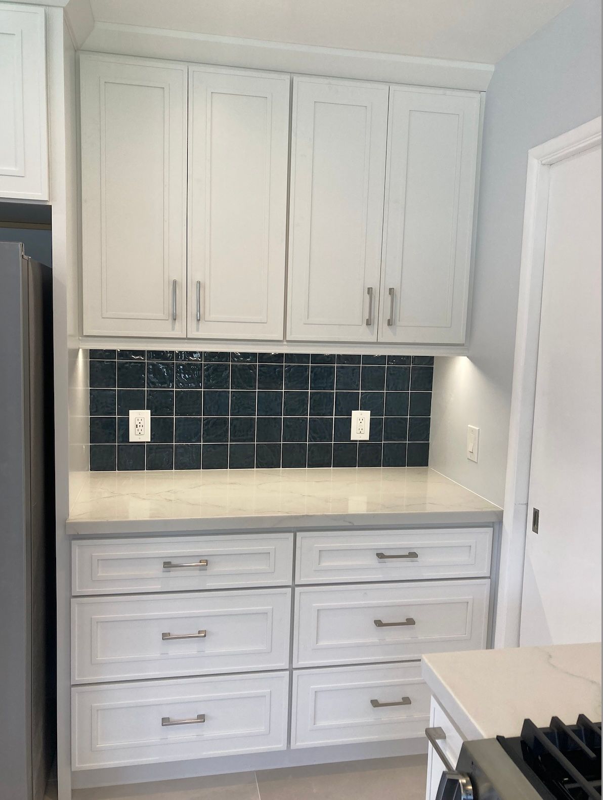 Kitchen with white cabinets, dark blue tile backsplash, and light gray countertops.