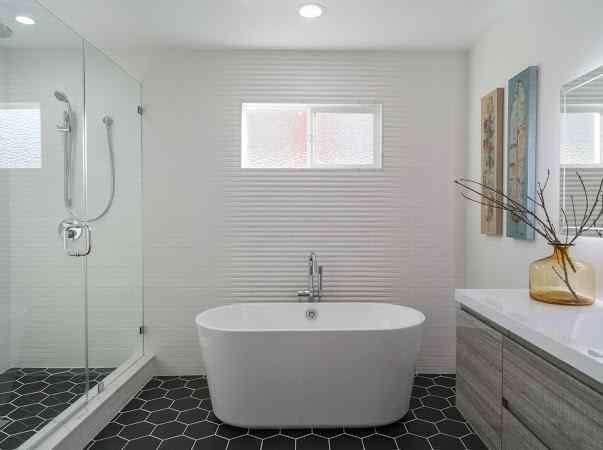 Modern bathroom with a freestanding tub, glass shower, and black hexagonal tile floor.
