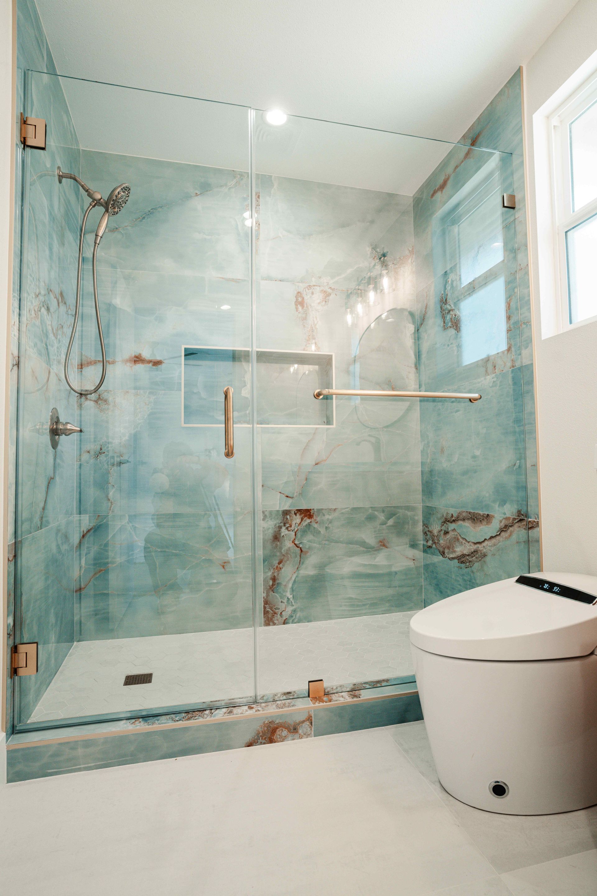 Modern bathroom with glass shower, blue-tiled walls, and a white toilet