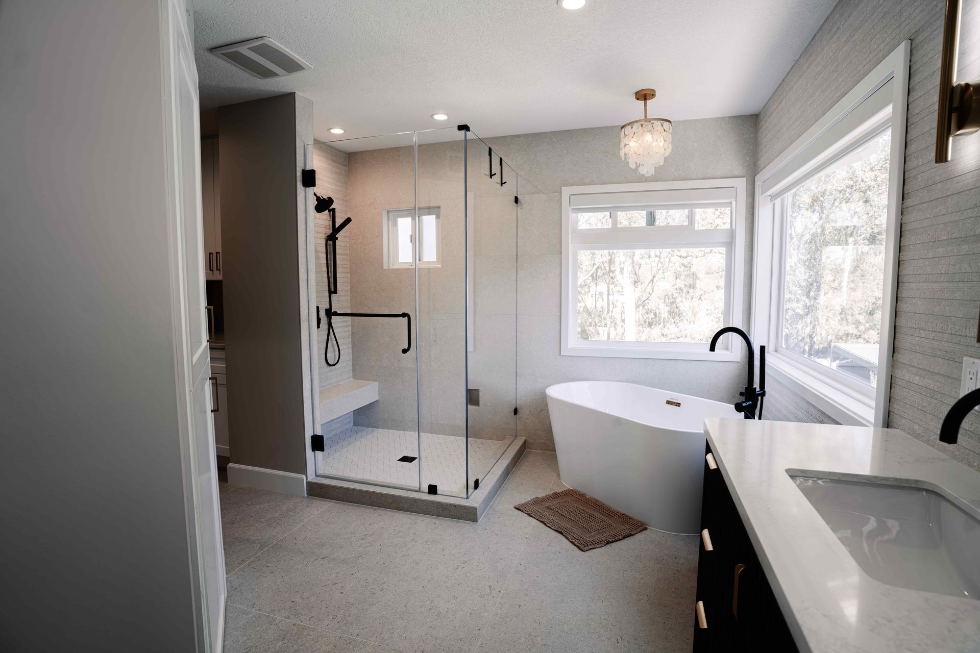 Modern bathroom with glass shower, freestanding tub, double vanity, and large windows