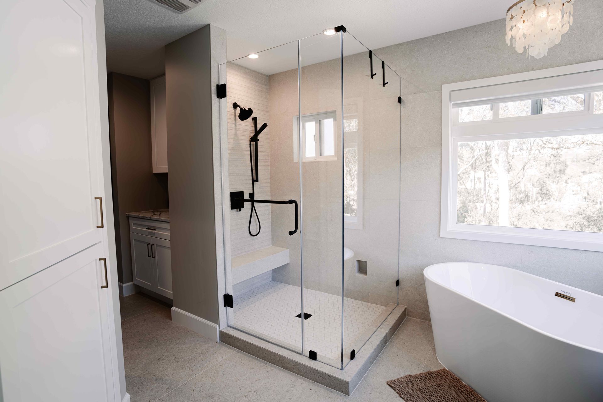 Bright modern bathroom with glass walk-in shower and freestanding tub near a large window
